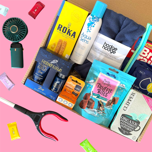 Hysterectomy recovery gift box on pink background featuring heat pack, cooling spray, sleep set, honey, peppermint tea, cheese biscuits and comfort essentials.